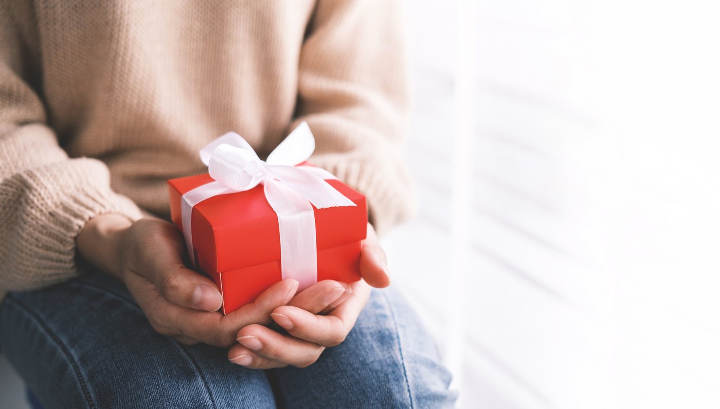 Decorative gift box with white bow ribbon. Gift in the hands